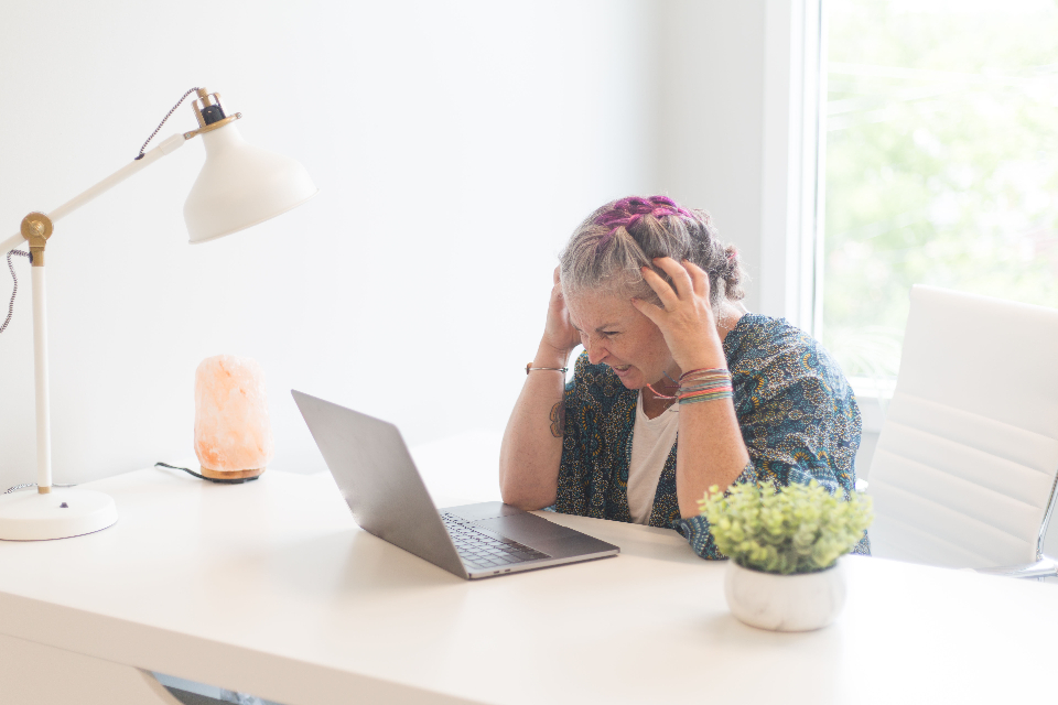 Femme HPI épuisée, la tête dans les mains devant son ordinateur