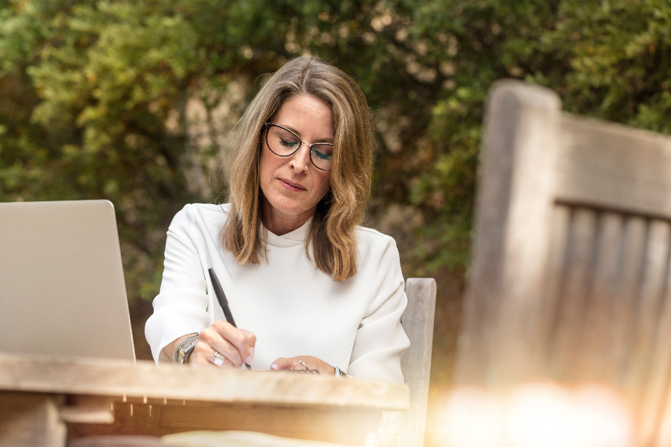 Femme qui réfléchit et prend des notes avant de se lancer à son compte